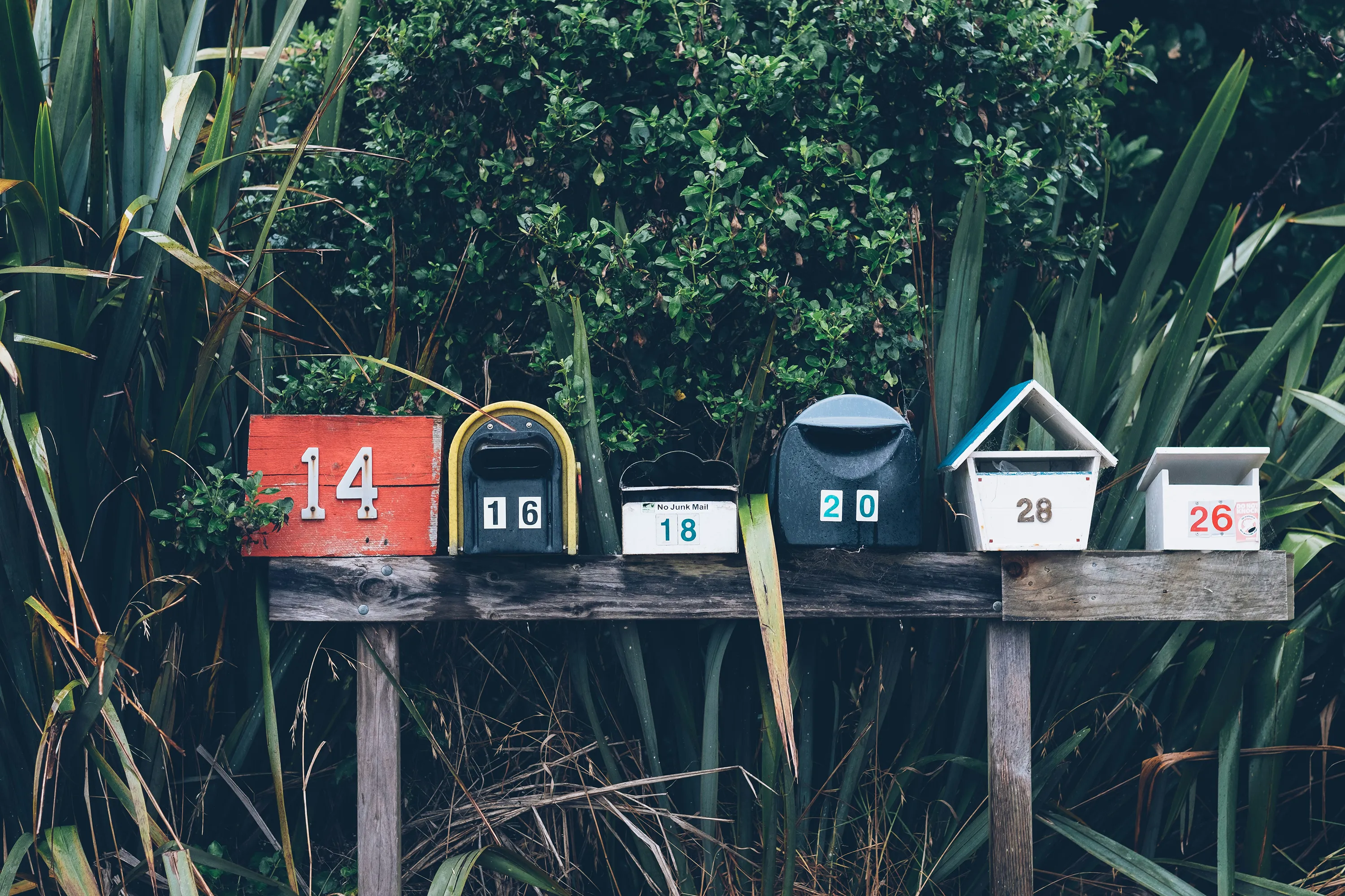 Mailboxes on posts with trees and hedges in the background